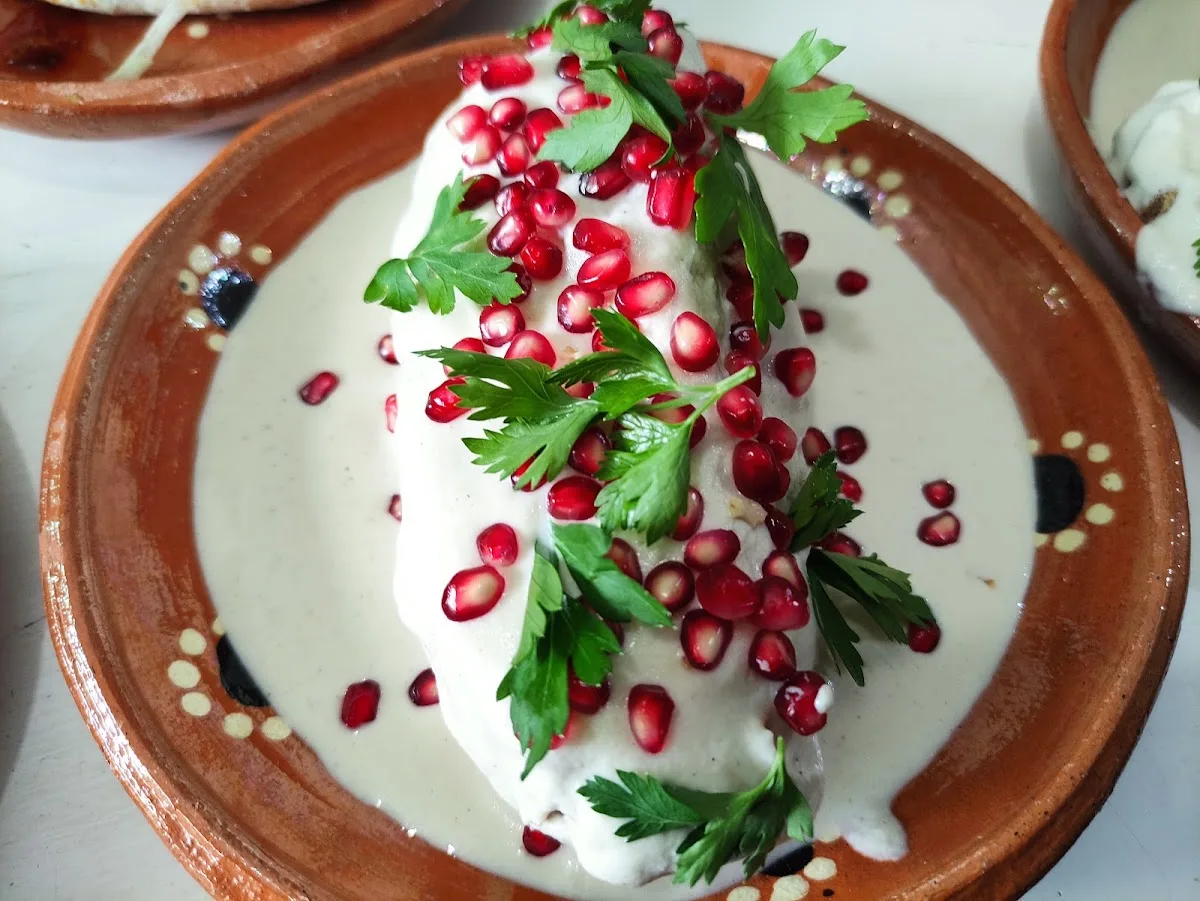 Chile en nogada con granada y perejil en plato de barro